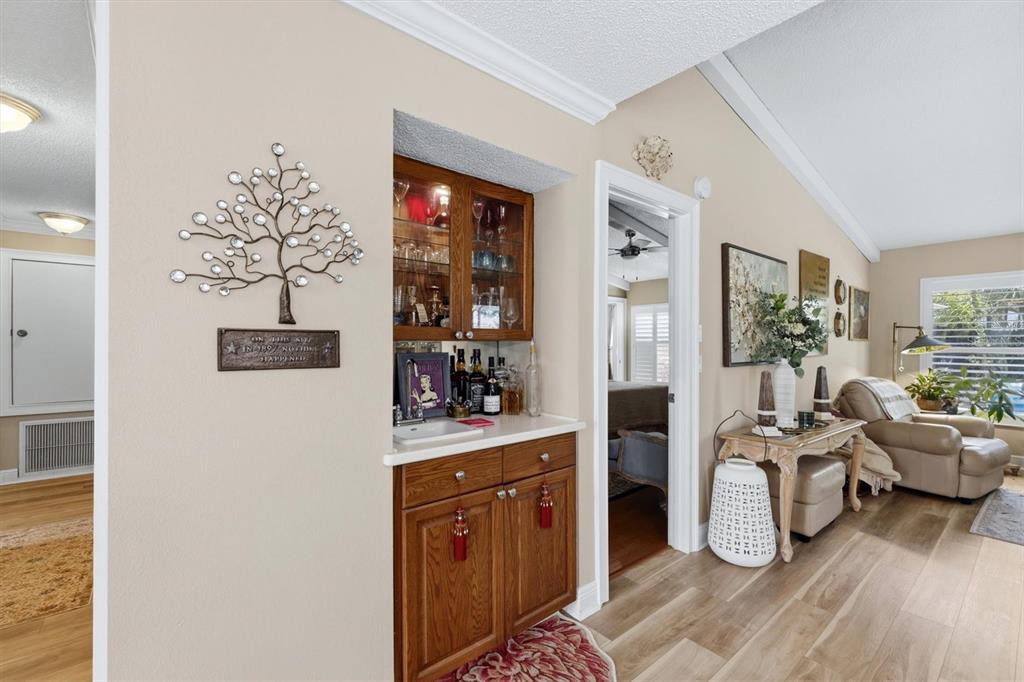 A wet bar with wooden cabinets and a decorative tree wall hanging sits between rooms — 3828 EASTON STREET, SARASOTA, FL