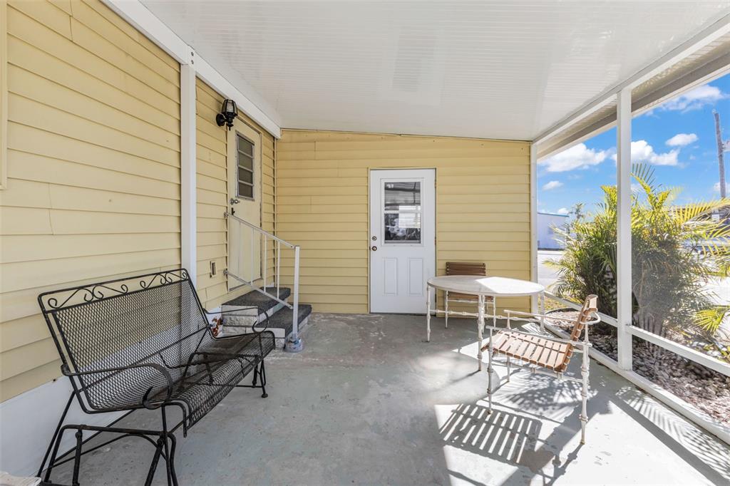A covered porch with yellow siding, a concrete floor, and outdoor furniture — 1891 ENGLEWOOD ROAD UNIT 119, ENGLEWOOD, FL