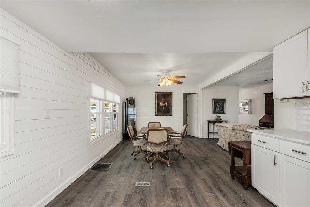 A dining area with shiplap walls, wood-look flooring, and a table with four chairs — 1891 ENGLEWOOD ROAD UNIT 119, ENGLEWOOD, FL