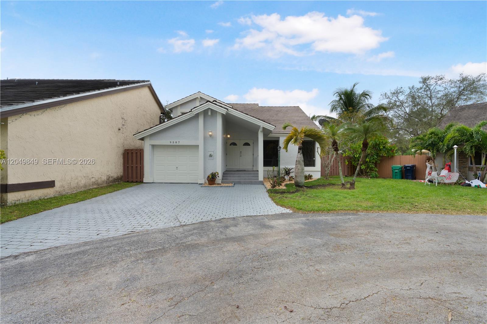 A single-story house with a paved driveway, a one-car garage, and a grassy front yard — 9587 SW 148th Ave Cir S, Miami FL 33196, MIAMI, FL