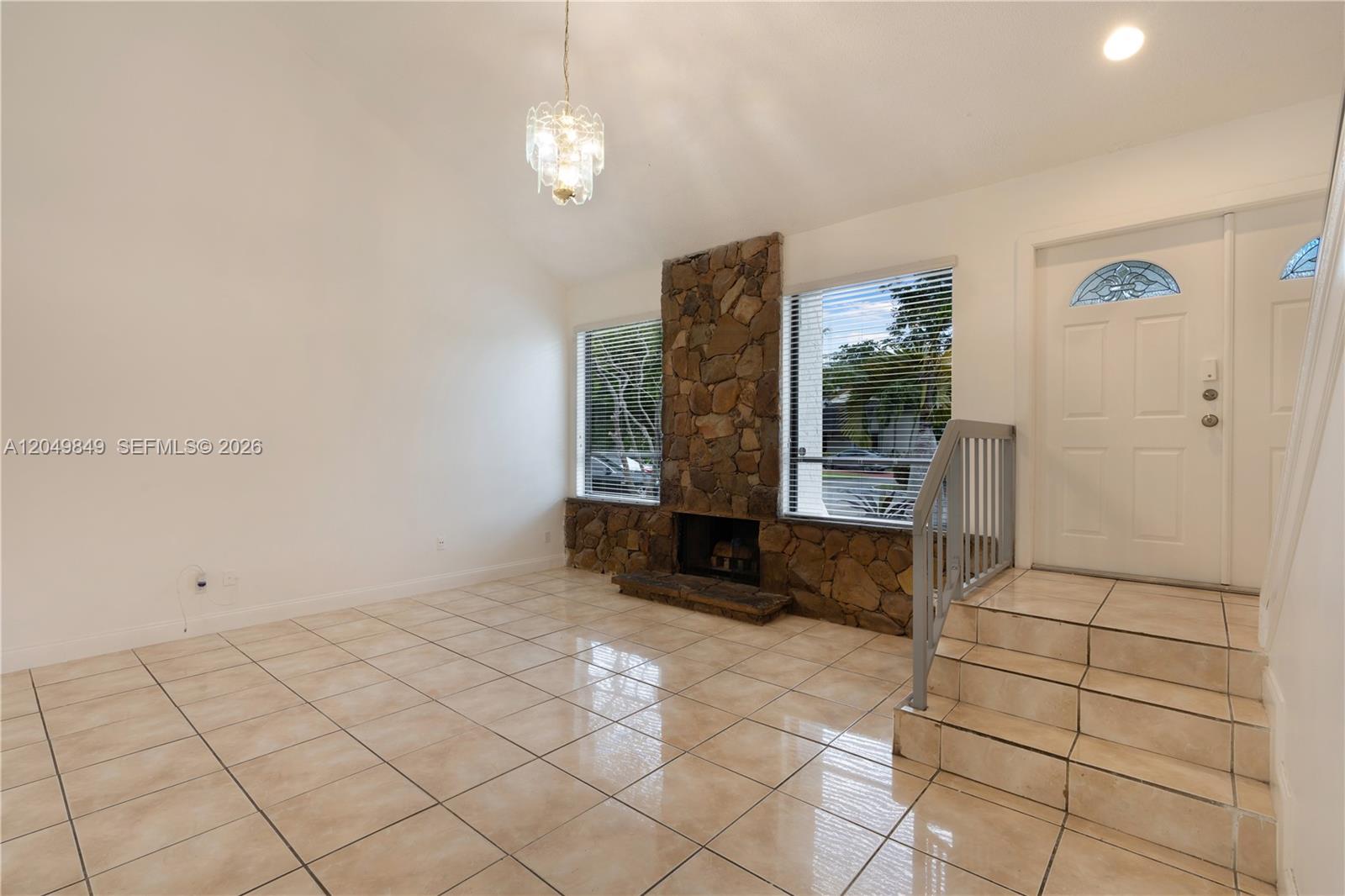 This living room features tile flooring, a stone fireplace, and a vaulted ceiling — 9587 SW 148th Ave Cir S, Miami FL 33196, MIAMI, FL