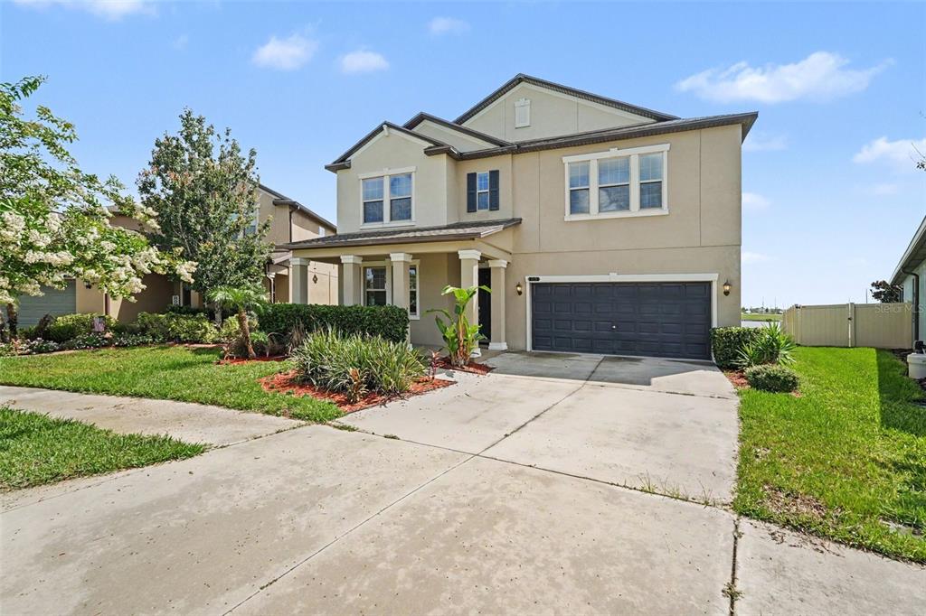 A two-story suburban house with a beige stucco exterior, a dark garage, and a driveway — 9173 SHADYSIDE LN, LAND O LAKES, FL