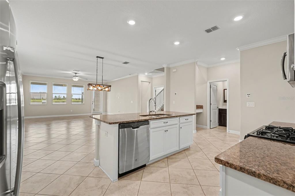 A kitchen with a granite-topped island and stainless steel dishwasher overlooks an open living area — 9173 SHADYSIDE LN, LAND O LAKES, FL