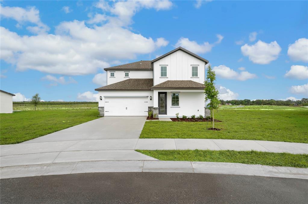 A two-story white house with a two-car garage sits on a grassy lot — 819 PONKAN COURT, BABSON PARK, FL