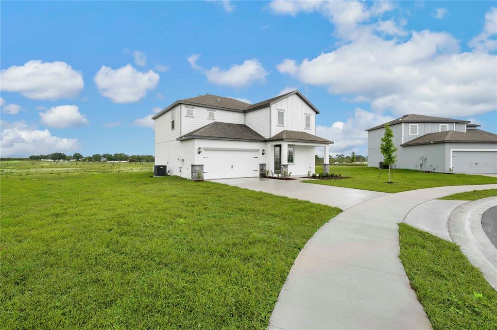 A two-story suburban house with a white exterior, two-car garage, and a concrete driveway — 819 PONKAN COURT, BABSON PARK, FL