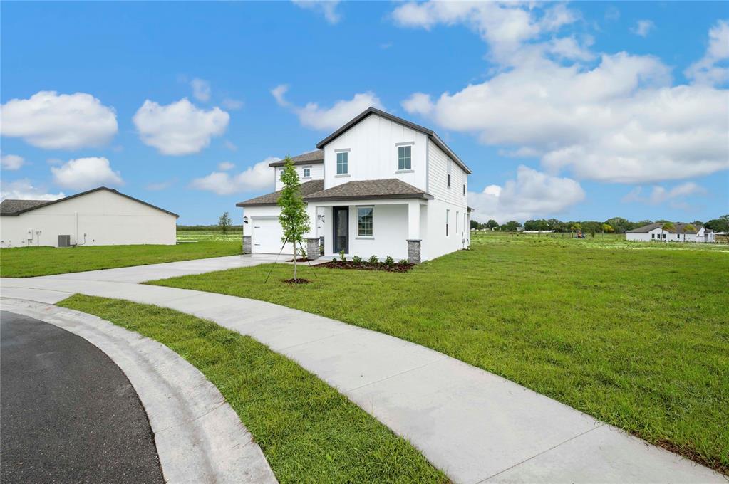 A two-story white house with a front porch and attached garage sits on a lawn — 819 PONKAN COURT, BABSON PARK, FL