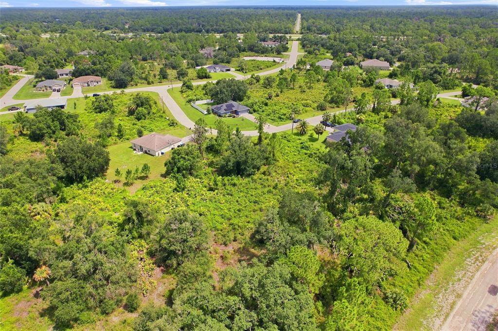 An aerial view shows a residential neighborhood with several houses surrounded by dense, wooded vegetation — NYBERG ROAD, NORTH PORT, FL