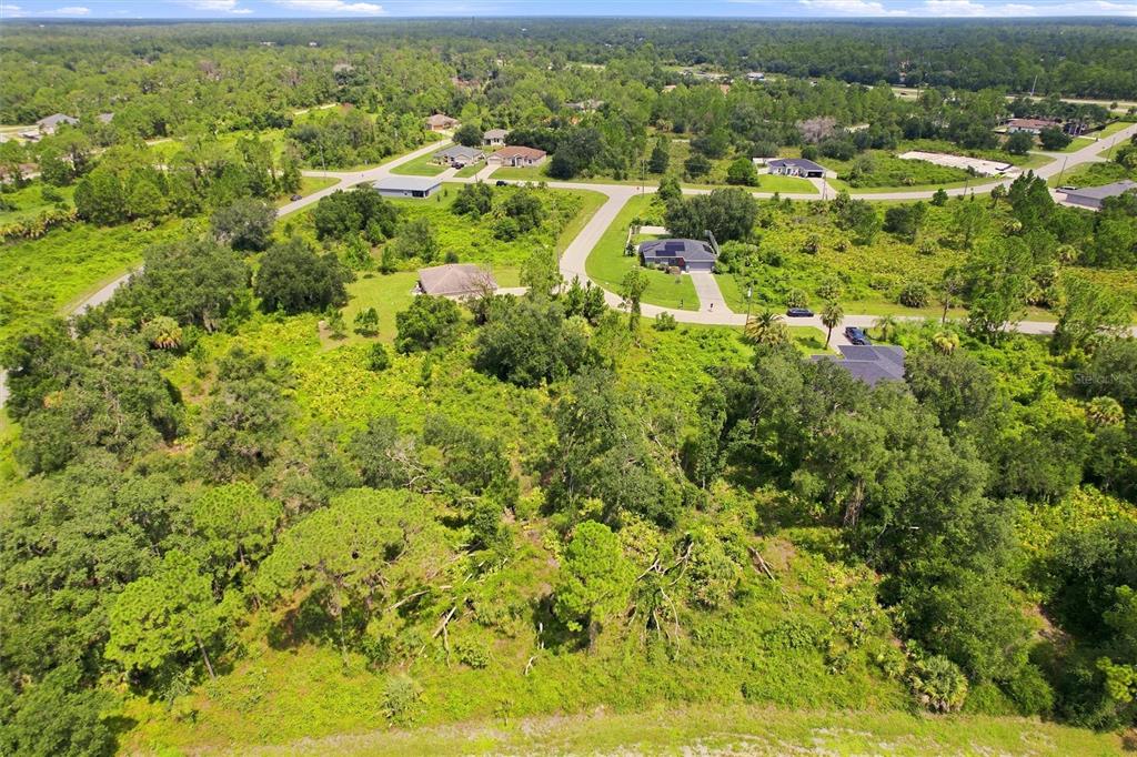 An aerial view shows a wooded residential lot with several houses and paved roads nearby — NYBERG ROAD, NORTH PORT, FL