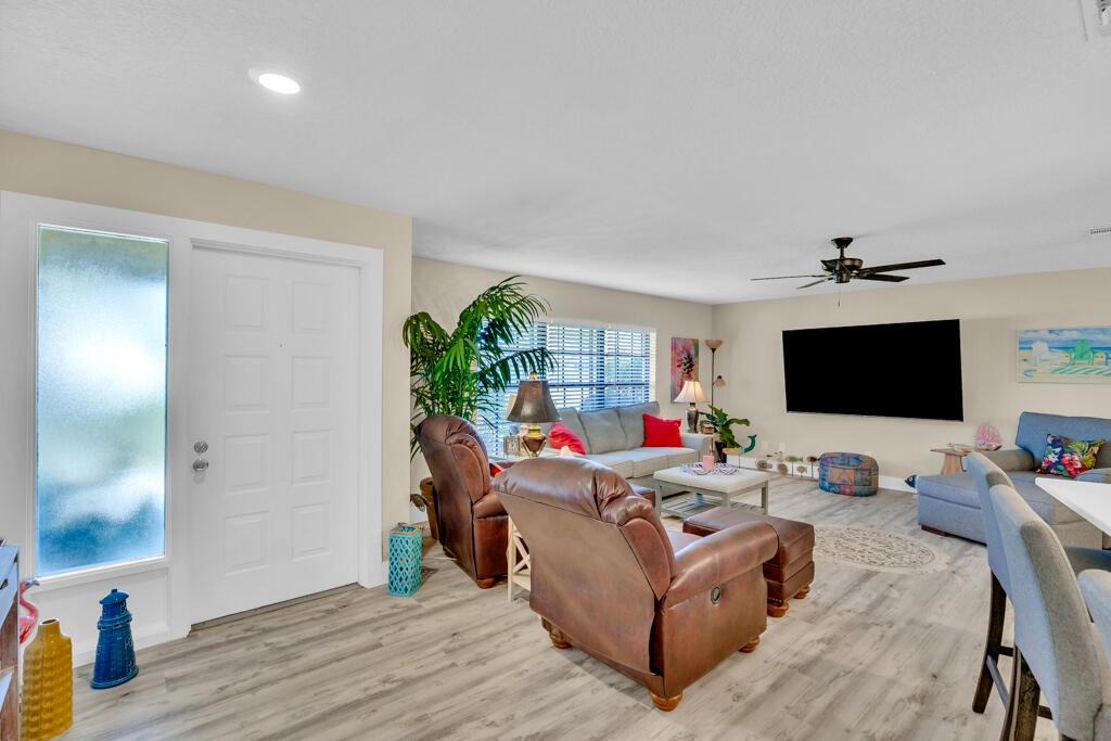 A living room features light wood-look flooring, a white front door, and a large television — 6655 110th Street, Sebastian FL 32958, SEBASTIAN, FL
