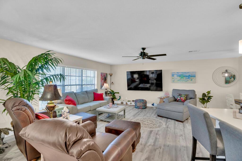 A living room features light wood-look flooring, a ceiling fan, and a wall-mounted television — 6655 110th Street, Sebastian FL 32958, SEBASTIAN, FL