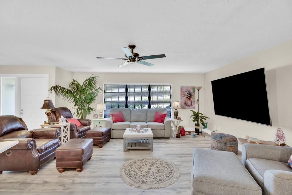 A living room features a gray sofa, brown leather armchairs, and a large wall-mounted television — 6655 110th Street, Sebastian FL 32958, SEBASTIAN, FL