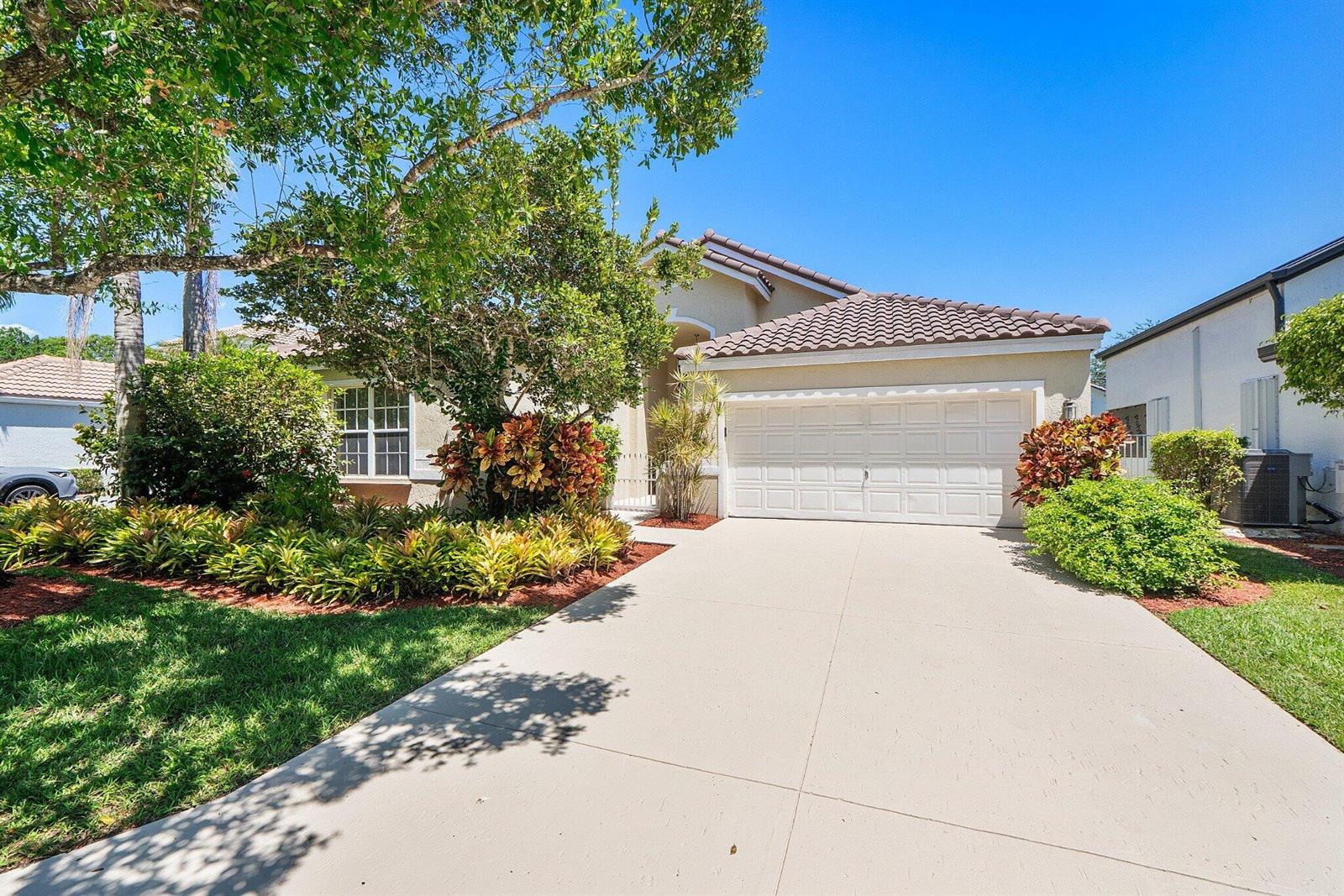 A single-story house with a white garage, tile roof, and landscaped front yard — 2016 Island Circle, Weston FL 33326, WESTON, FL
