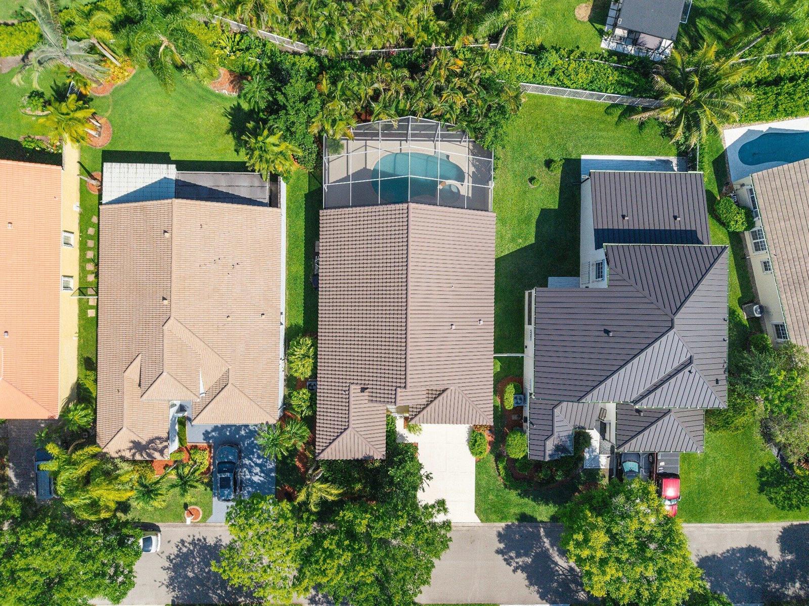 An aerial view shows three suburban houses with tiled roofs, swimming pools, and landscaped yards — 2016 Island Circle, Weston FL 33326, WESTON, FL