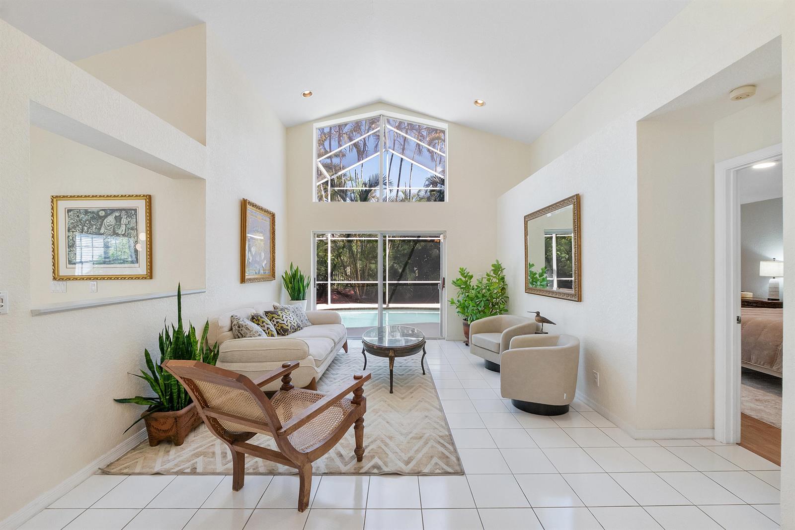 A bright living room features vaulted ceilings, tile flooring, and a view of a pool — 2016 Island Circle, Weston FL 33326, WESTON, FL