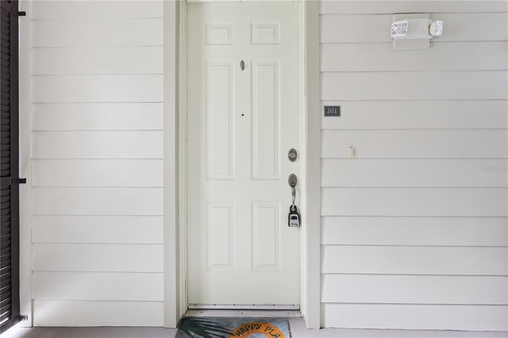 A white front door with a lockbox and unit number 201 on the exterior wall — 762 CELEBRATION AVENUE UNIT 2201, CELEBRATION, FL