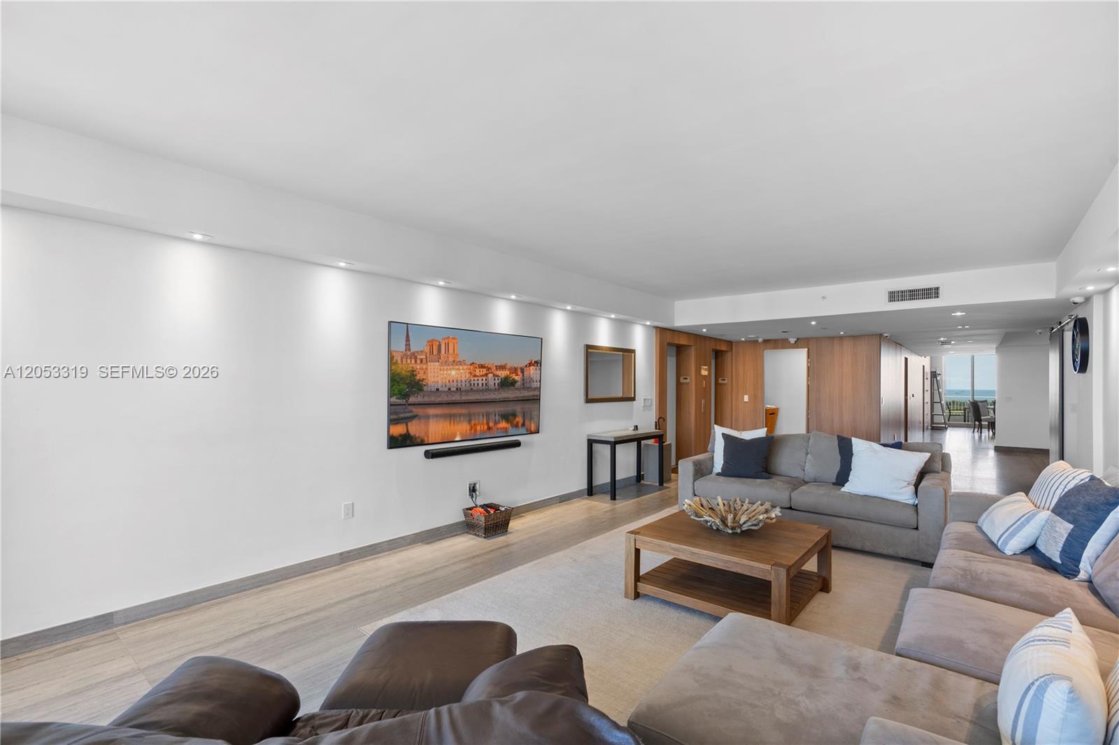 A living room features a wall-mounted television, gray sectional sofa, and light wood flooring — 1600 SW 1st Ave # 714, Miami FL 33129, MIAMI, FL