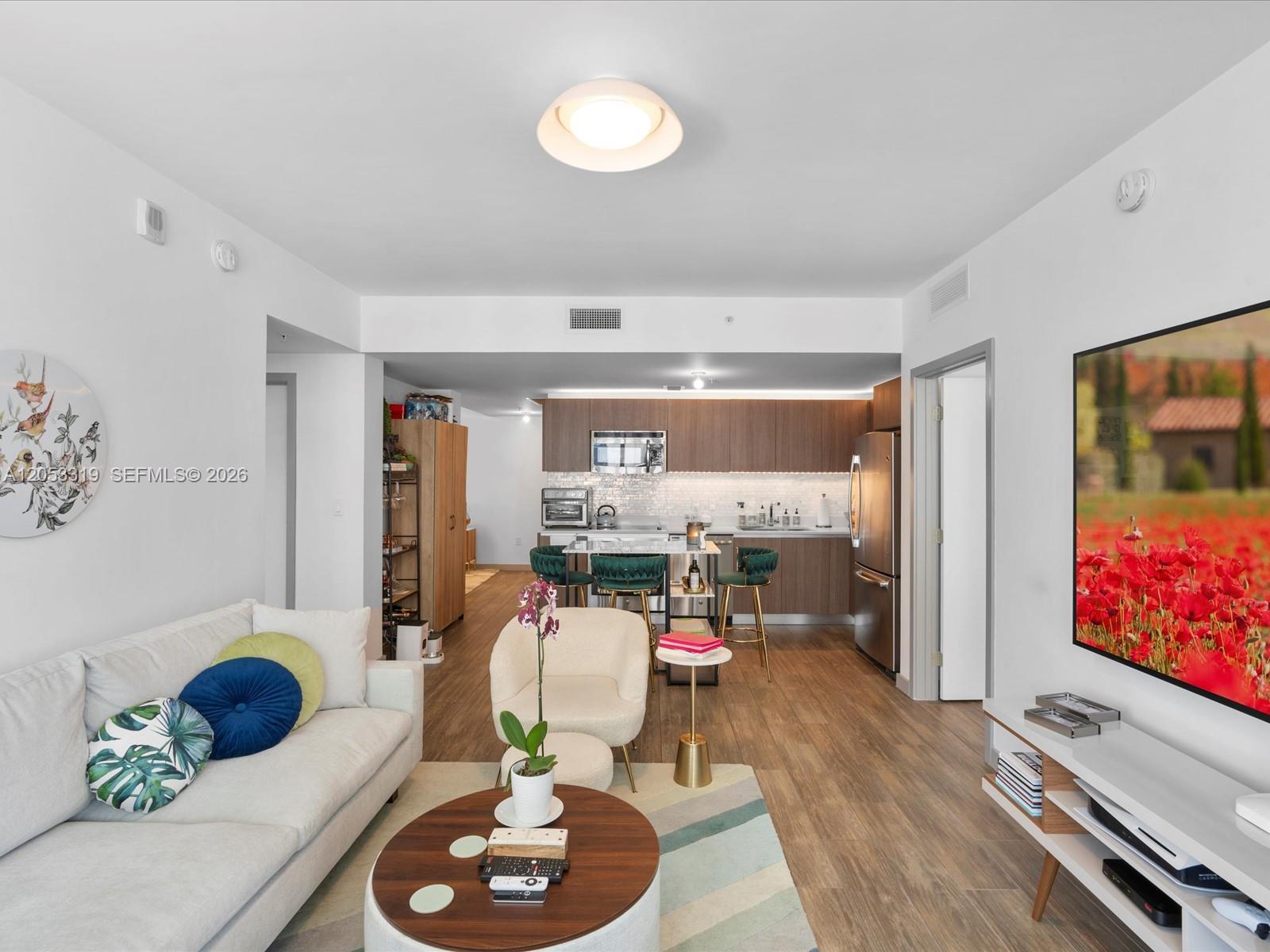 A modern living room with a white sofa flows into an open kitchen with bar seating — 1600 SW 1st Ave # 714, Miami FL 33129, MIAMI, FL
