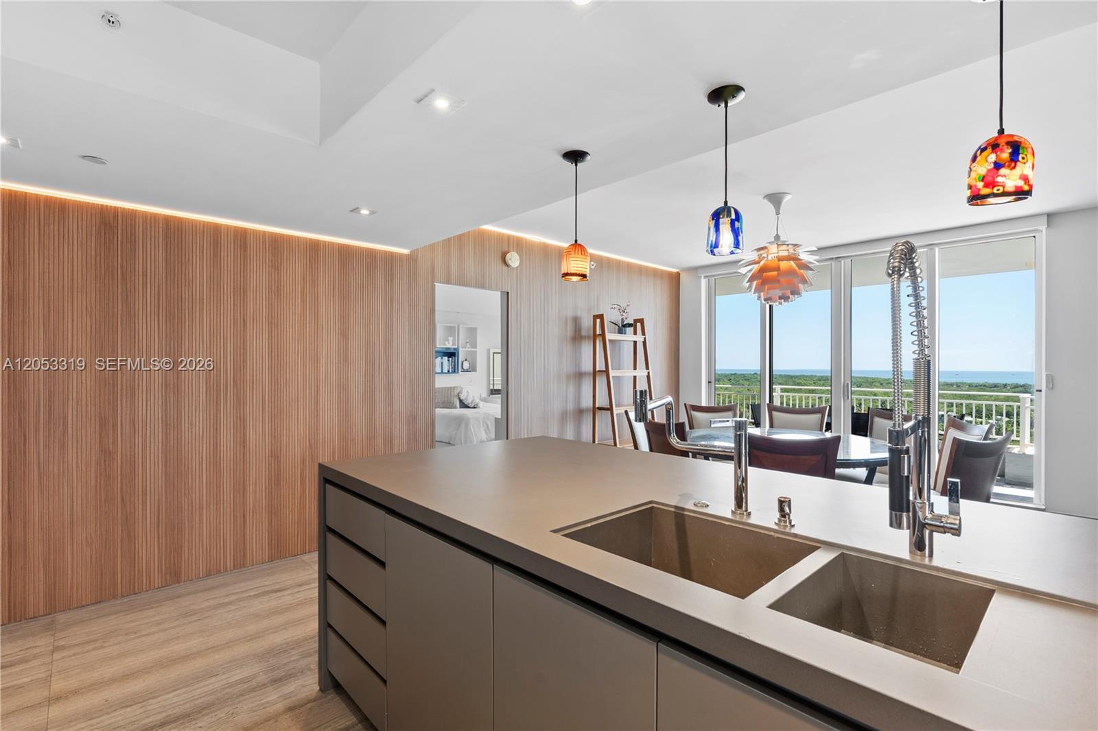 A modern kitchen island with a double sink faces a dining area and balcony — 1600 SW 1st Ave # 714, Miami FL 33129, MIAMI, FL