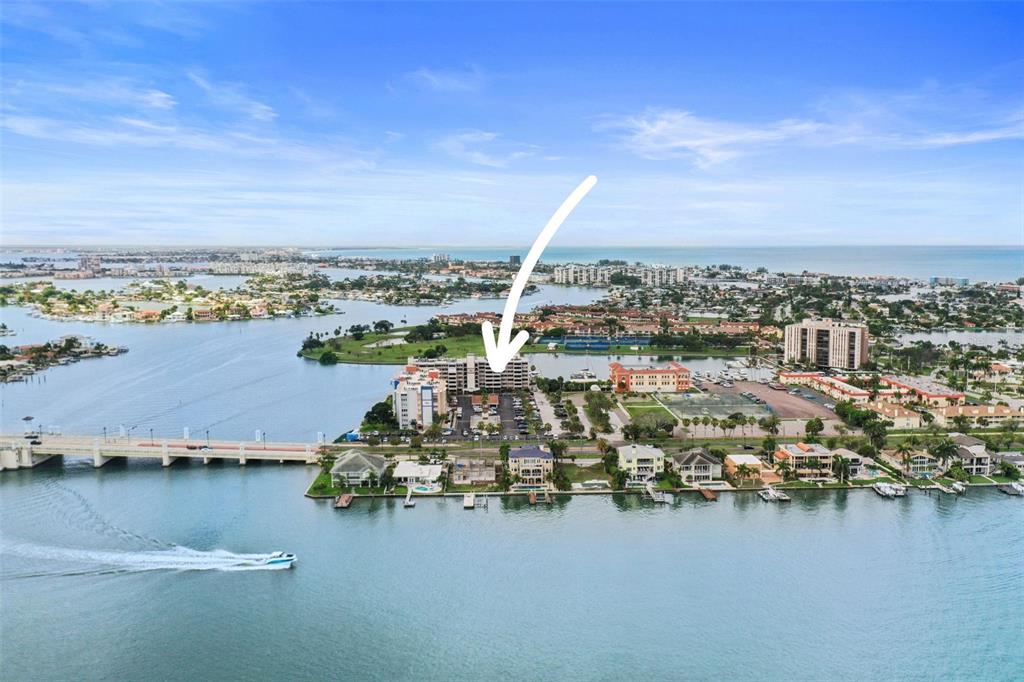 An aerial view shows a waterfront condominium complex with a bridge and surrounding residential area — 450 TREASURE ISLAND CAUSEWAY UNIT 502, TREASURE ISLAND, FL