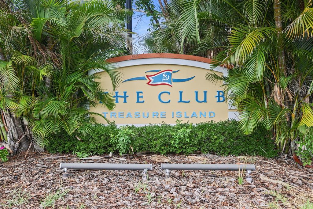 A sign for The Club Treasure Island stands surrounded by palm trees and landscaping — 450 TREASURE ISLAND CAUSEWAY UNIT 502, TREASURE ISLAND, FL