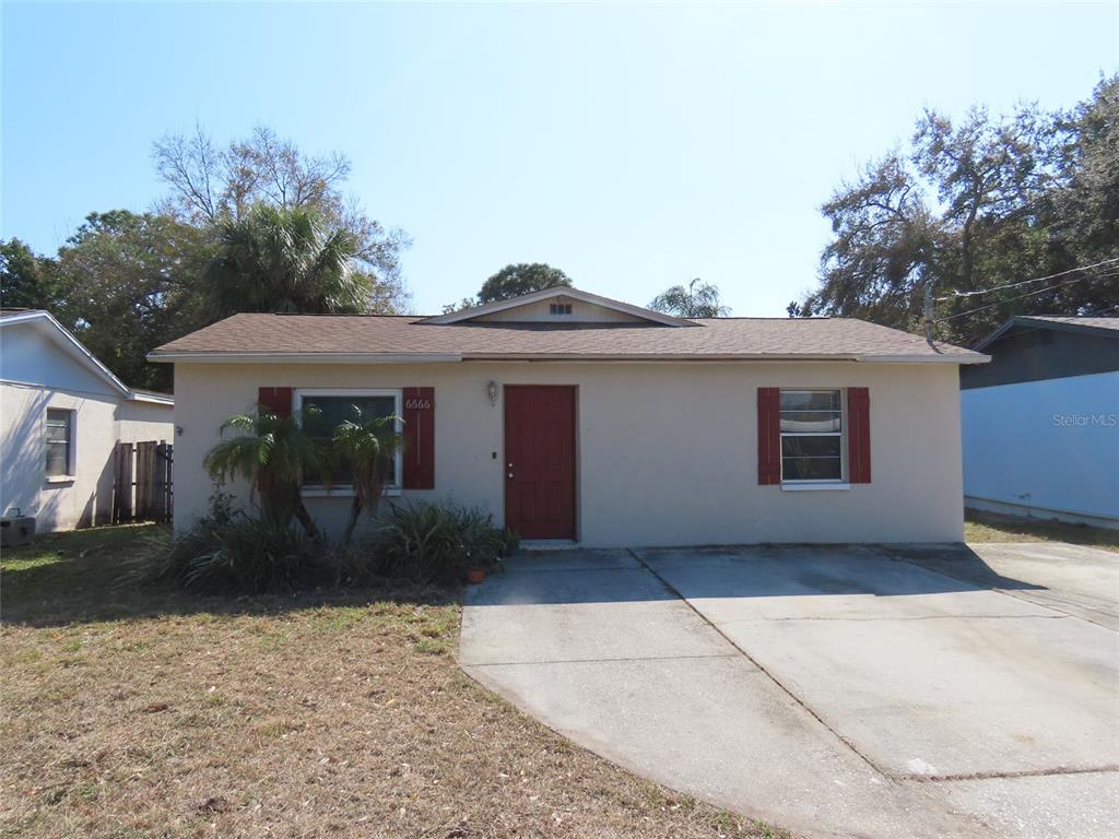 A single-story house with a beige exterior, red front door, and a concrete driveway — 6666 56TH AVENUE N, ST PETERSBURG, FL