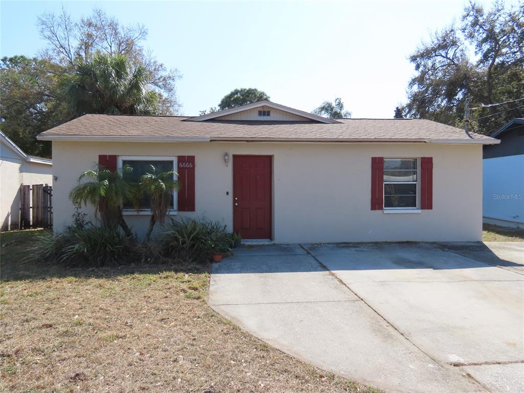 A single-story house with a beige exterior, red front door, and a concrete driveway — 6666 56TH AVENUE N, ST PETERSBURG, FL