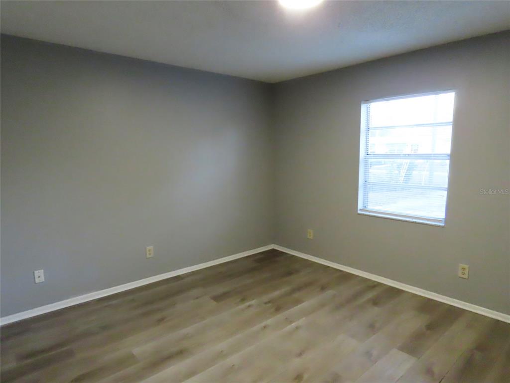 An empty bedroom features gray walls, light wood-look flooring, and a single window — 6666 56TH AVENUE N, ST PETERSBURG, FL