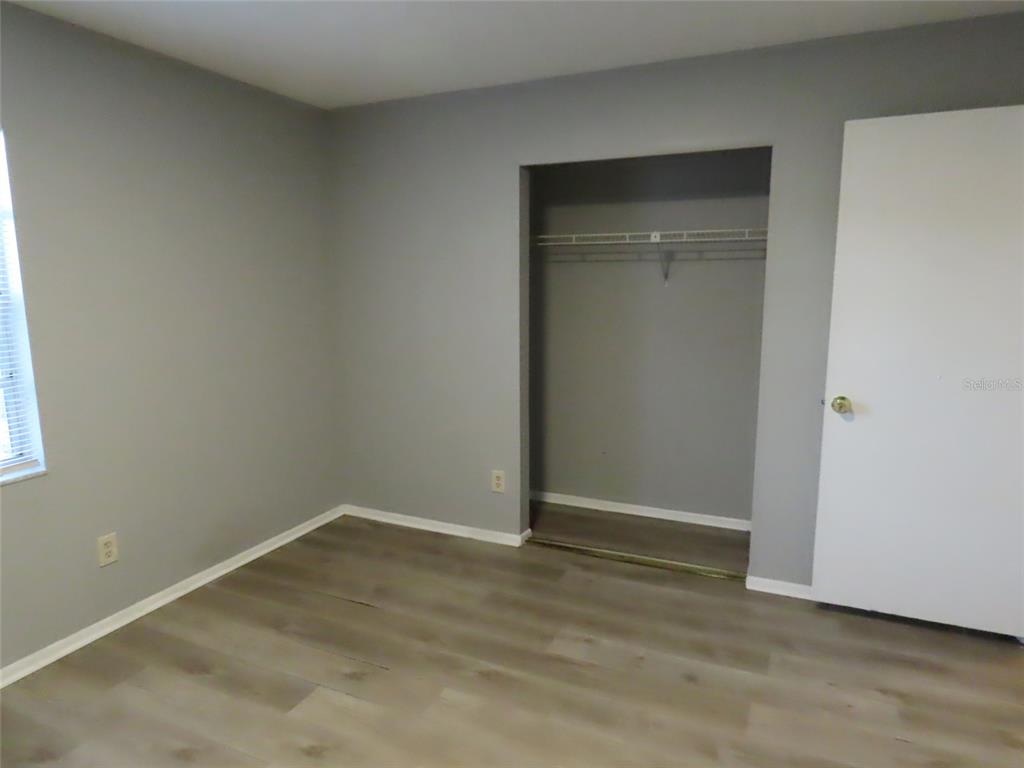 An empty bedroom features gray walls, light wood-look flooring, and an open closet — 6666 56TH AVENUE N, ST PETERSBURG, FL