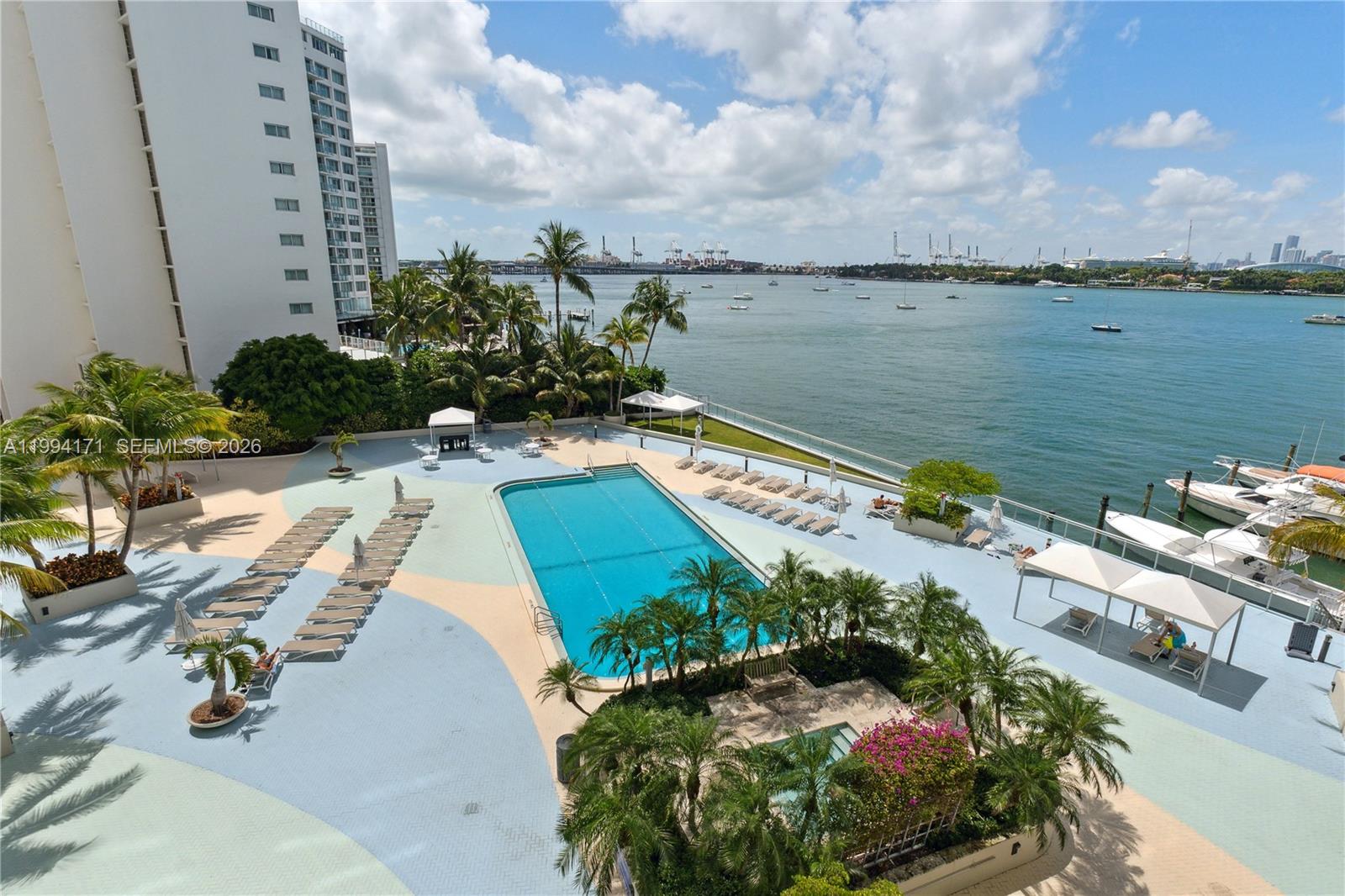 An elevated view of a swimming pool deck with lounge chairs overlooking a bay — 1200 West Ave # 528, Miami Beach FL 33139, MIAMI BEACH, FL