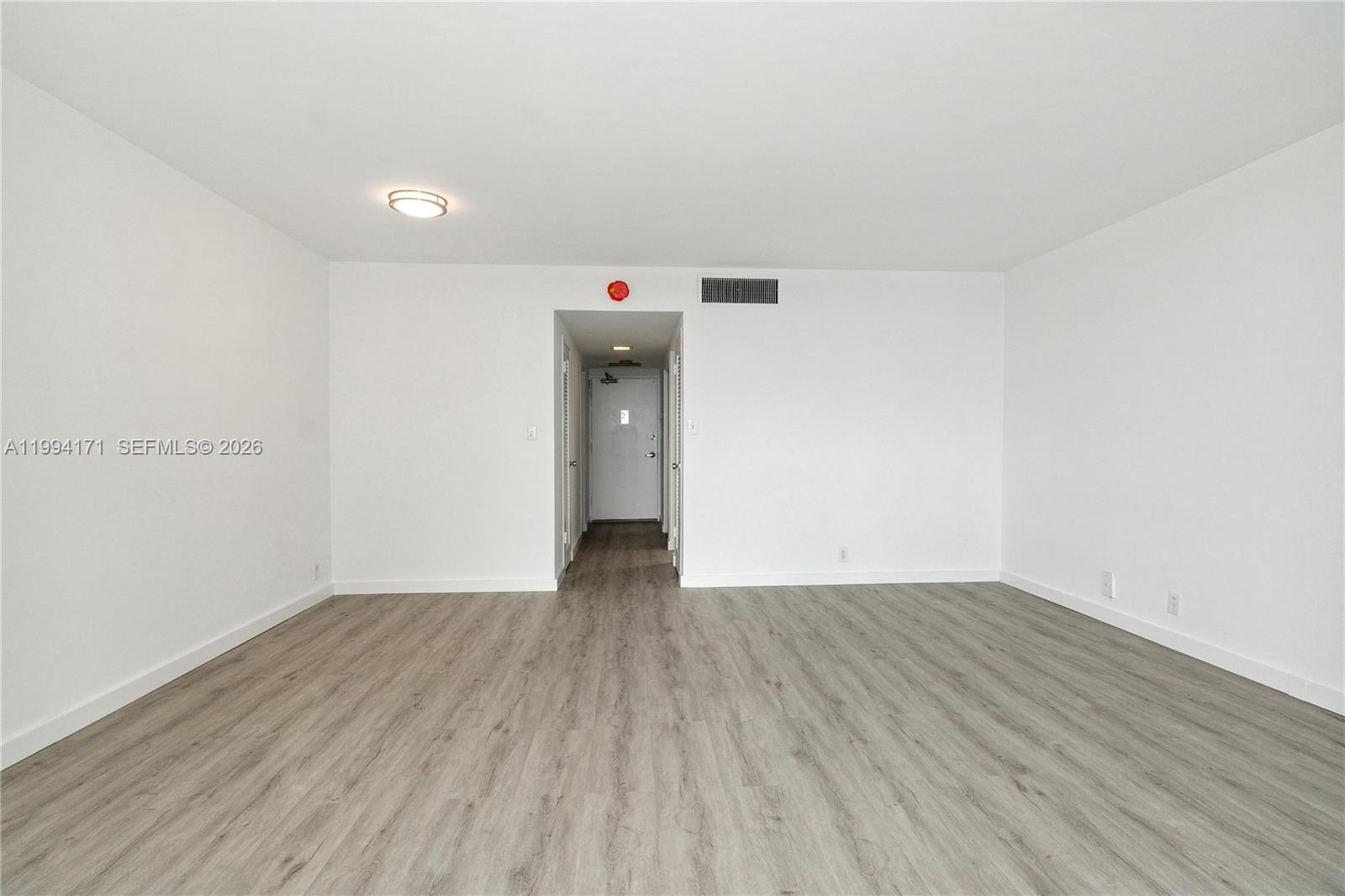 A minimalist room features white walls, light wood-look flooring, and a central hallway entrance — 1200 West Ave # 528, Miami Beach FL 33139, MIAMI BEACH, FL