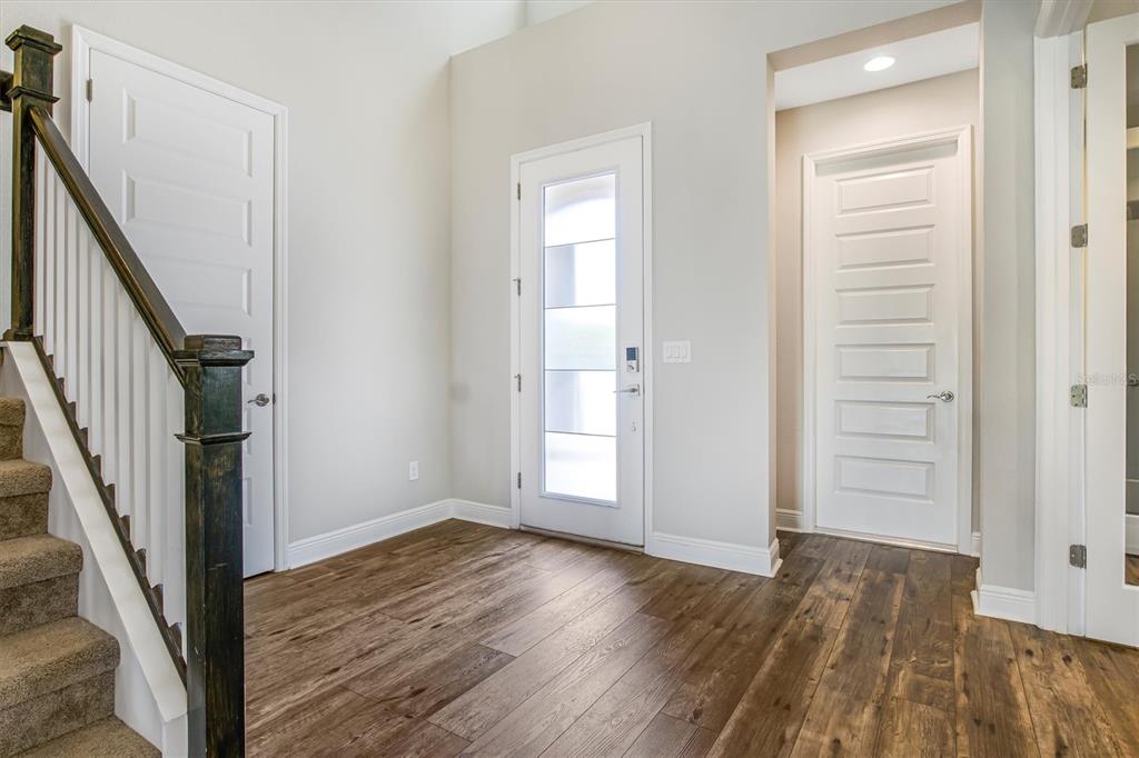 An entryway with wood-look flooring, a staircase, a front door, and two interior doors — 12859 SATIN LILY DRIVE, RIVERVIEW, FL