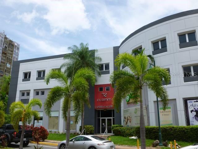 A multi-story commercial building with a gray and white facade and palm trees in front — 107 GONZALEZ GUISTI AVE., GUAYNABO, PR