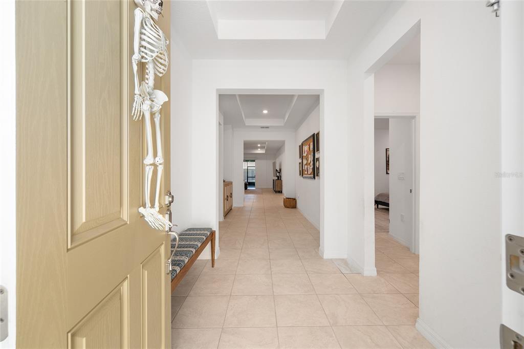 A bright entryway features light tile flooring, a bench, and a skeleton decoration on the door — 7431 SW 65TH PLACE ROAD, OCALA, FL