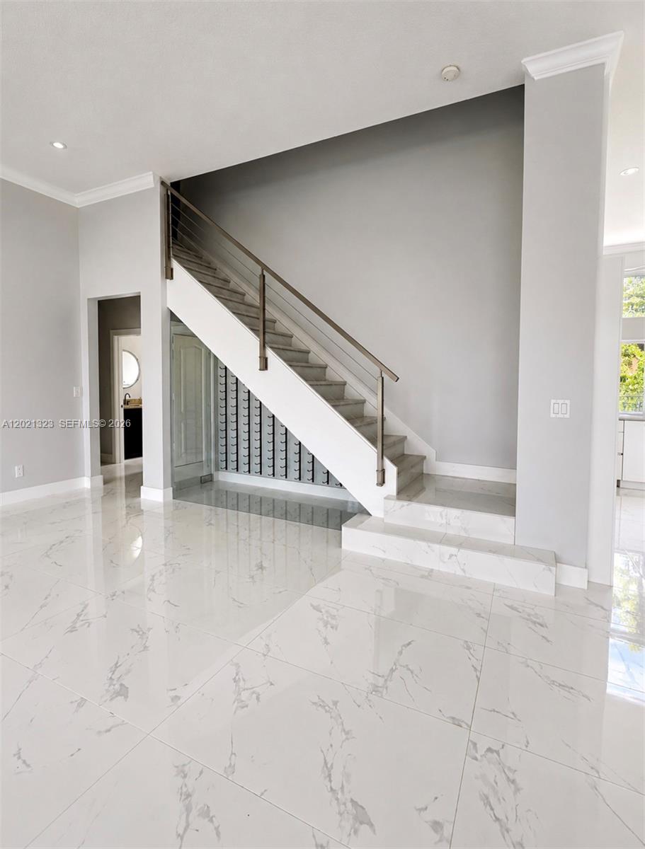 A modern staircase with a metal railing sits above a wine rack in a room — 354 Mallard Rd # o, Weston FL 33327, WESTON, FL