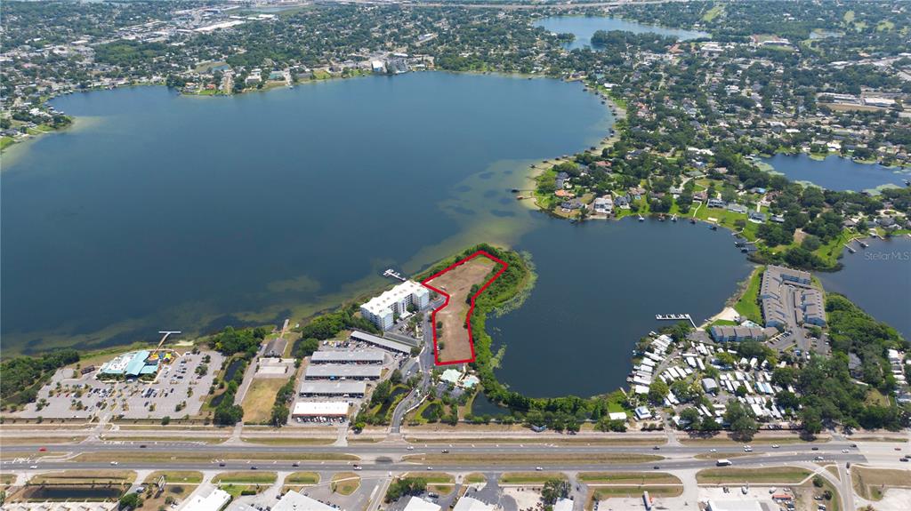 An aerial view shows a vacant waterfront lot outlined in red between two lakes — 4171 N ORANGE BLOSSOM TRAIL, ORLANDO, FL