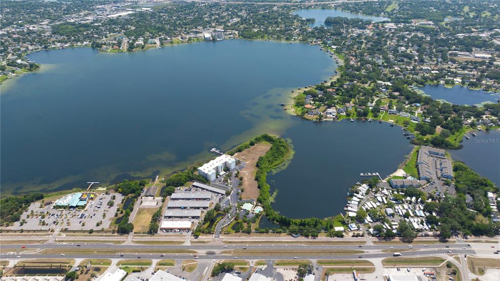 An aerial view shows a large lake surrounded by residential neighborhoods, commercial buildings, and a highway — 4171 N ORANGE BLOSSOM TRAIL, ORLANDO, FL