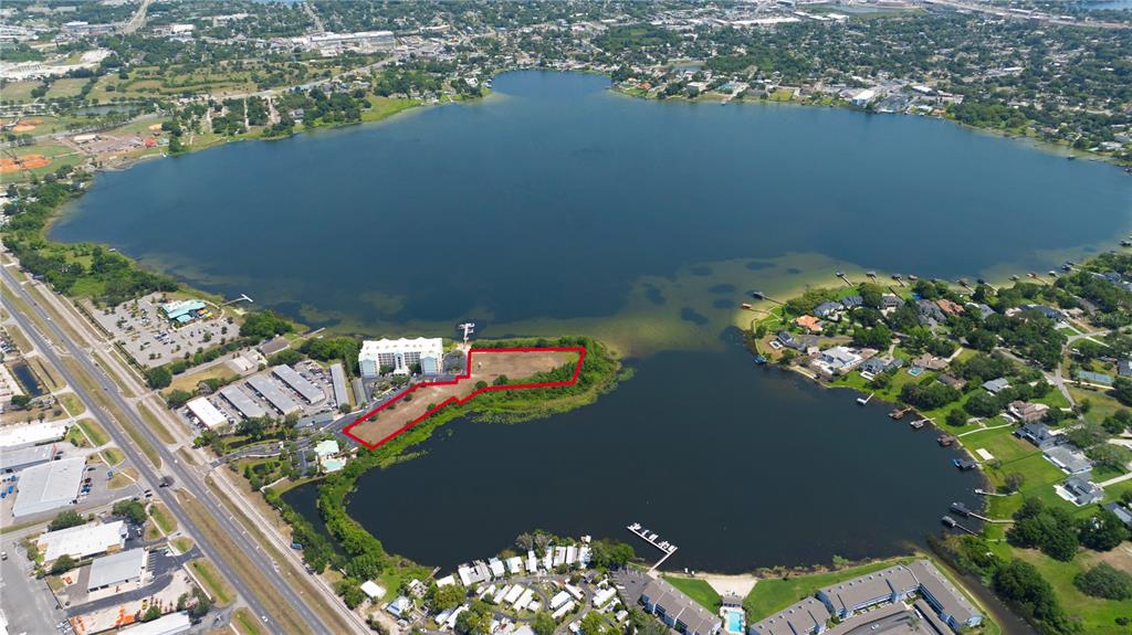 An aerial view shows a vacant waterfront lot outlined in red next to a hotel — 4171 N ORANGE BLOSSOM TRAIL, ORLANDO, FL