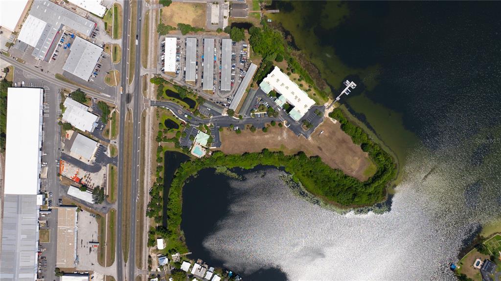 This aerial view shows a commercial property with buildings, parking lots, and a lakefront dock — 4171 N ORANGE BLOSSOM TRAIL, ORLANDO, FL