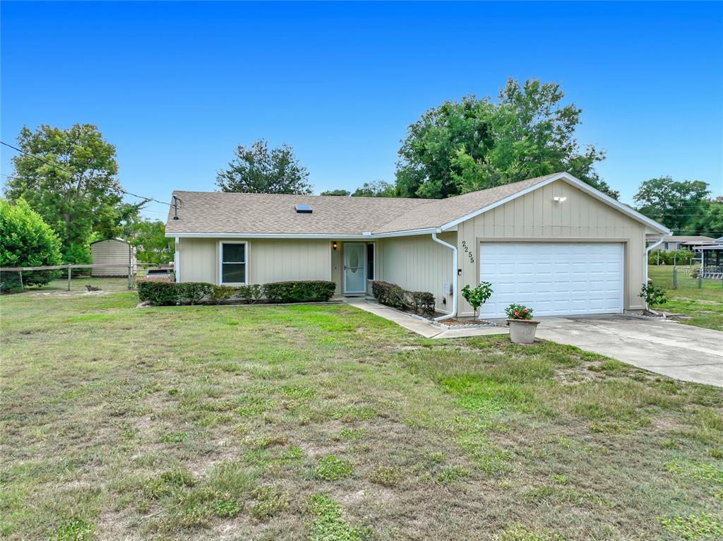 A single-story house with tan siding, a white garage door, and a grassy front yard — 2255 CROAT STREET, MOUNT DORA, FL