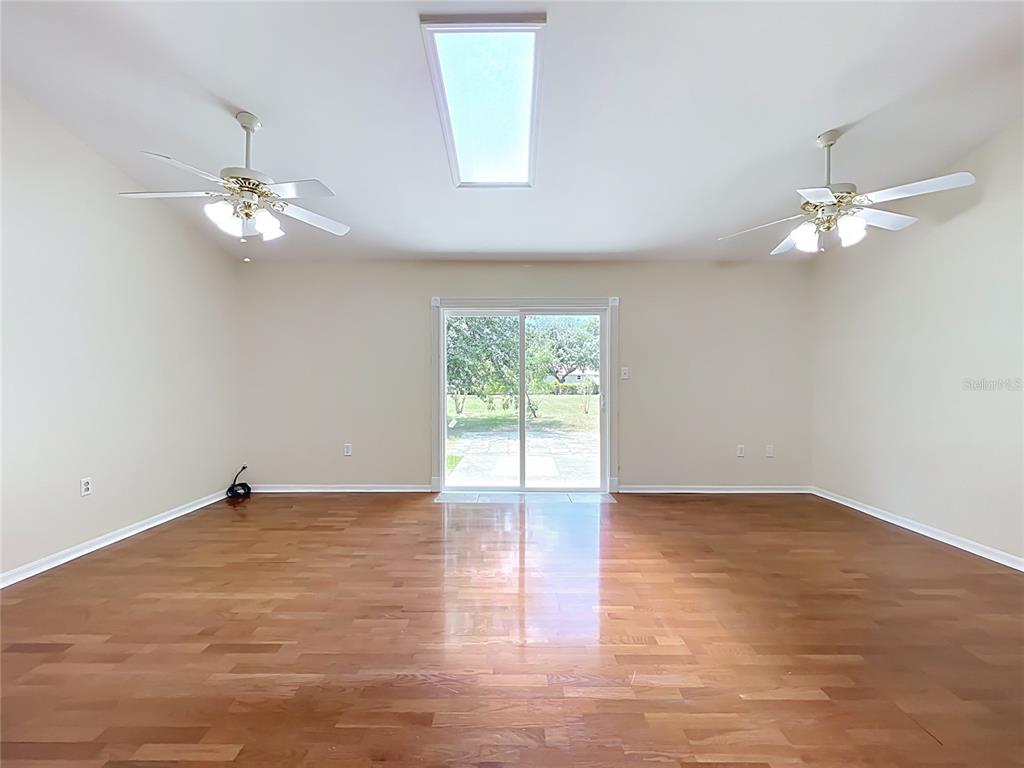 A spacious room with hardwood floors, two ceiling fans, a skylight, and sliding glass doors — 2255 CROAT STREET, MOUNT DORA, FL