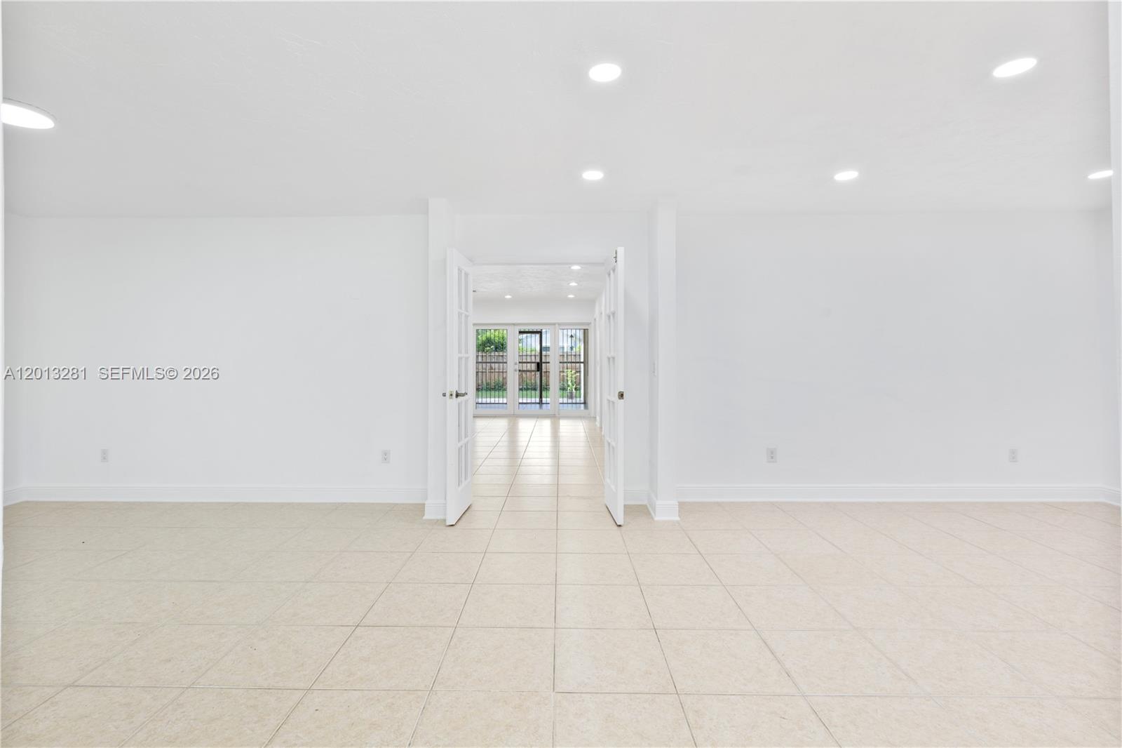 A bright, empty room with white walls, tile flooring, and French doors leading outside — 5770 SW 55 st, Miami FL 33155, MIAMI, FL