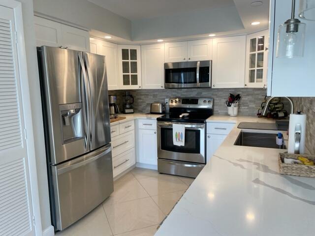 A modern kitchen features white cabinetry, stainless steel appliances, and light-colored quartz countertops — 500 Ocean Trail Way # 204, Jupiter FL 33477, JUPITER, FL