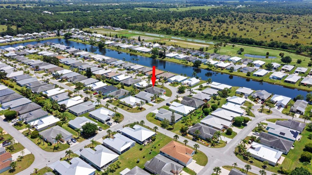 An aerial view shows a residential neighborhood with a canal and a red arrow pointing to a house — 6527 ALHELI, FORT PIERCE, FL