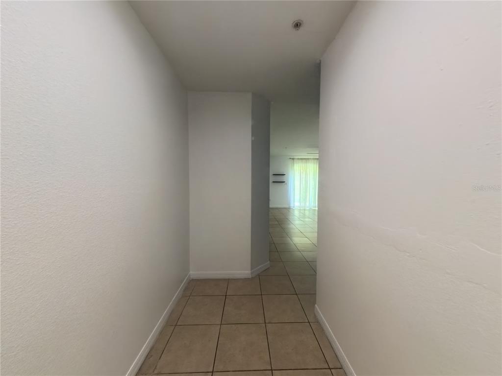 A tiled hallway leads to an open living area with large windows and light curtains — 215 GLOWING PEACE LANE UNIT 86, ORLANDO, FL