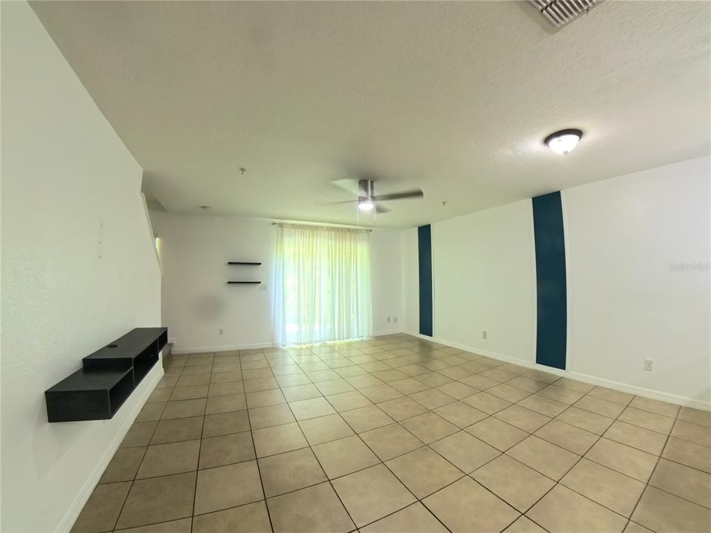 A living room features white walls, tile flooring, a ceiling fan, and a sliding glass door — 215 GLOWING PEACE LANE UNIT 86, ORLANDO, FL