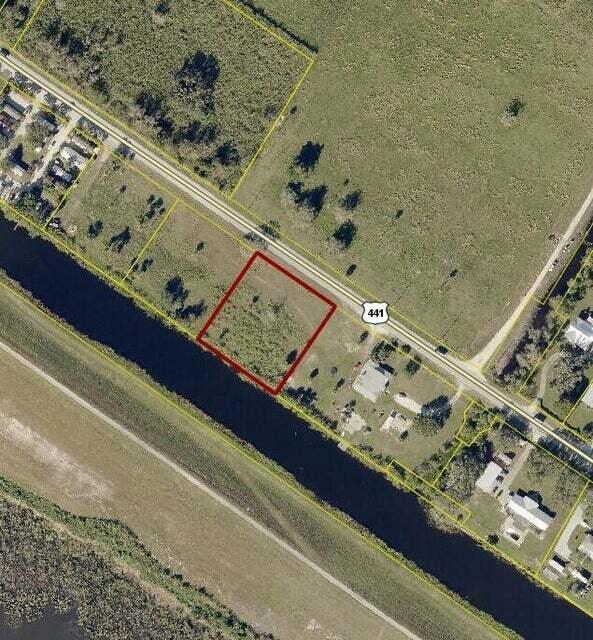An aerial view shows a vacant rectangular lot outlined in red next to a canal — 5646 Us Hwy 441, Okeechobee FL 34974, OKEECHOBEE, FL
