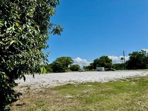 A large, flat, cleared dirt lot sits under a clear blue sky near some trees — 5646 Us Hwy 441, Okeechobee FL 34974, OKEECHOBEE, FL