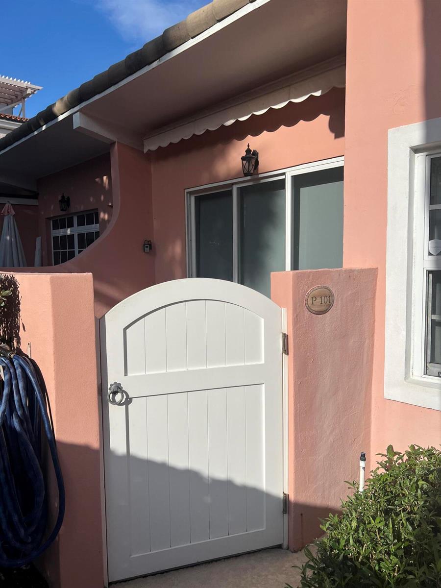 A white arched gate leads to the entrance of a pink stucco building unit — 142 Peruvian Avenue # 101, Palm Beach FL 33480, PALM BEACH, FL