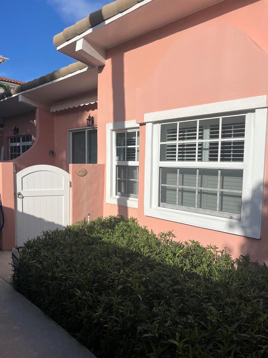 A peach-colored exterior wall features a white gate, a window with shutters, and landscaping — 142 Peruvian Avenue # 101, Palm Beach FL 33480, PALM BEACH, FL