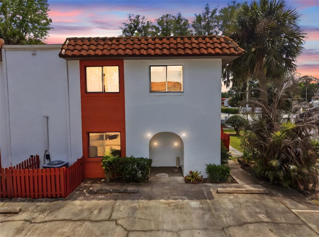 A two-story townhouse with white stucco walls, red brick accents, and a tiled roof — 910 BIG TREE ROAD UNIT 202, SOUTH DAYTONA, FL